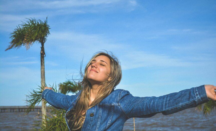 woman spreading arms near body of water