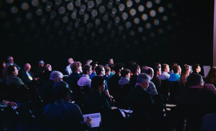 crowd of people sitting on chairs inside room