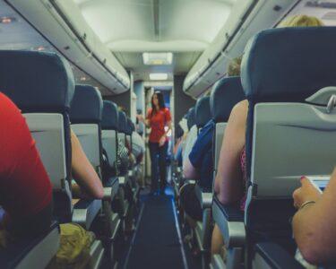 flight attendant standing between passenger seat