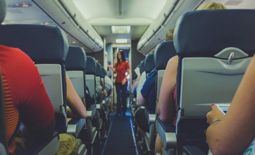 flight attendant standing between passenger seat