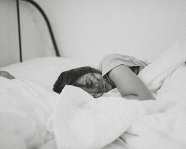 grayscale photo of sleeping woman lying on bed