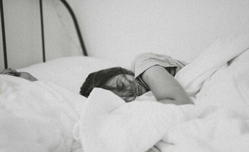 grayscale photo of sleeping woman lying on bed