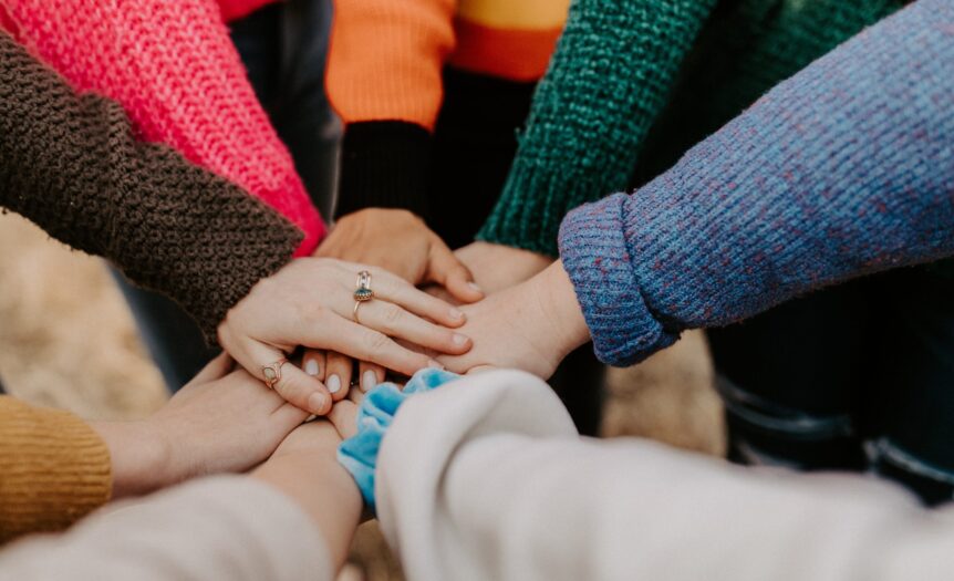 person in red sweater holding babys hand