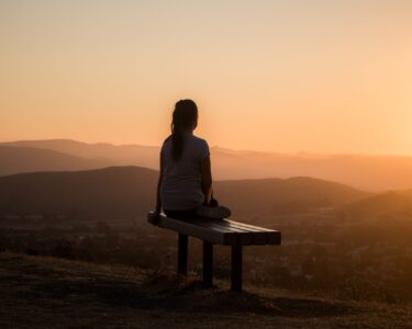 woman sitting on bench over viewing mountain