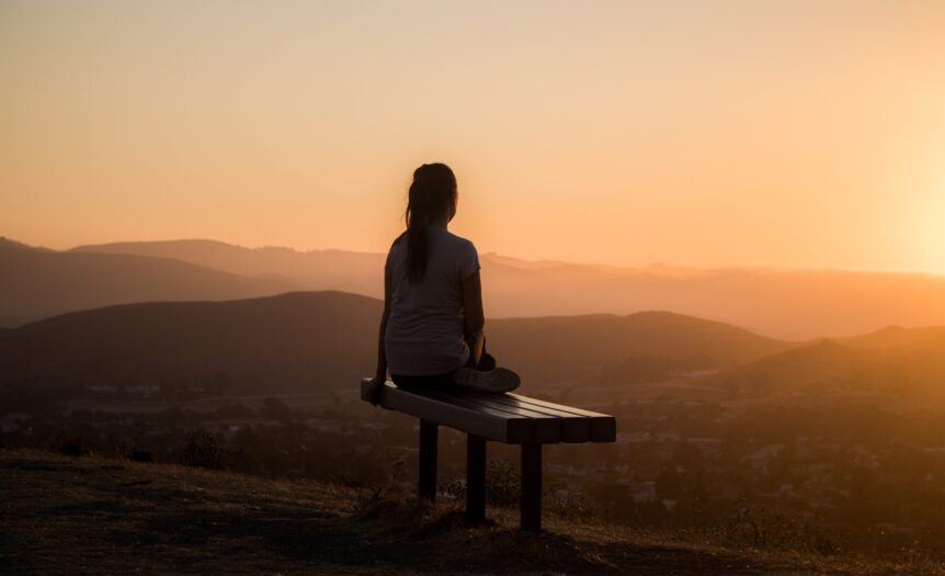 woman sitting on bench over viewing mountain