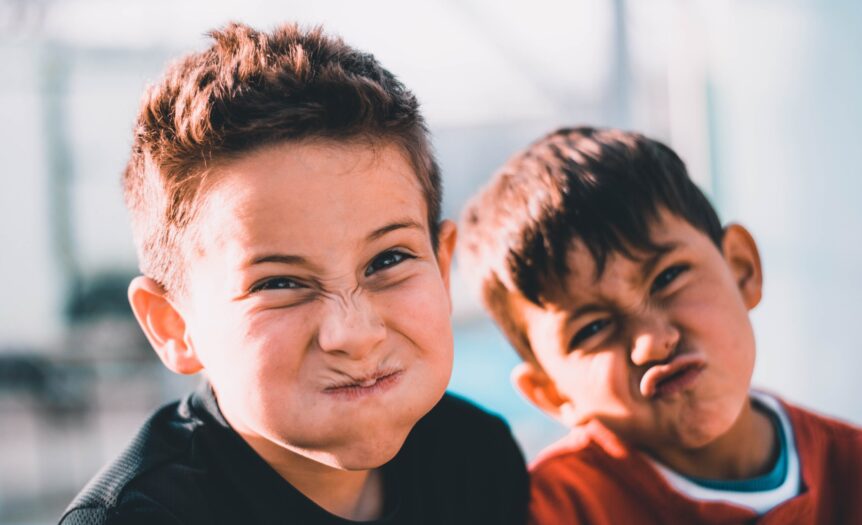 shallow focus photography of two boys doing wacky faces