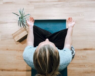 woman in black shirt and gray pants sitting on brown wooden bench