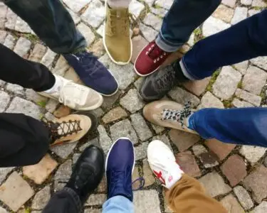 Circle of sneakers on cobblestone pavement representing diversity and urban fashion.