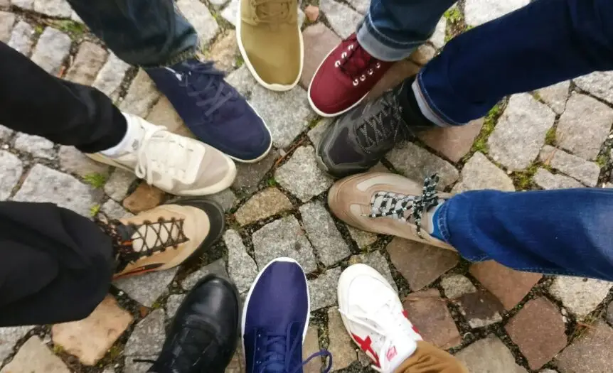 Circle of sneakers on cobblestone pavement representing diversity and urban fashion.