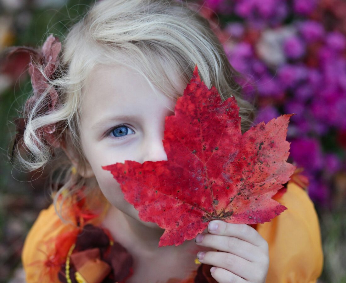 girl holding red maple leaf