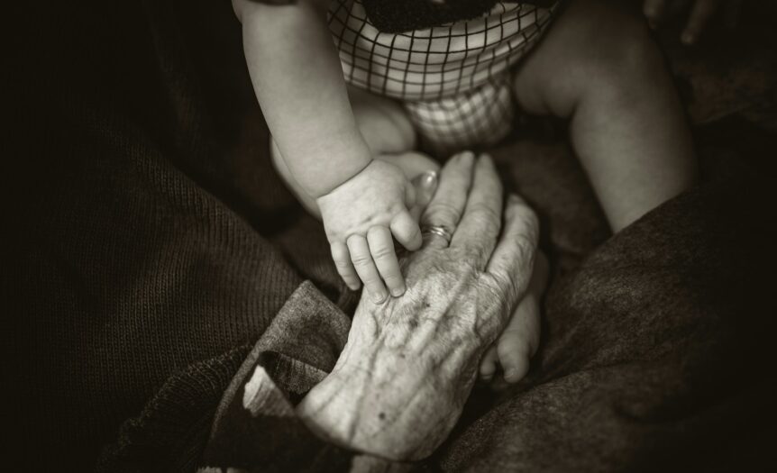 an older woman holding a baby's hand