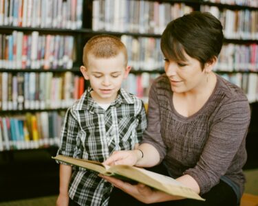 boy in gray sweater beside boy in gray and white plaid dress shirt