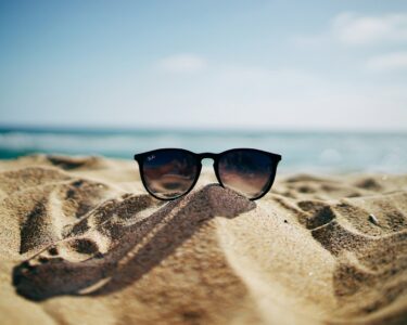 black Ray-Ban Wayfarer sunglasses on beach sand