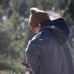 a person standing in a field looking at a cell phone