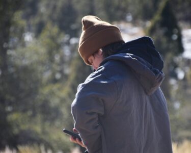a person standing in a field looking at a cell phone