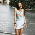 woman in white tank top and blue denim shorts standing on road during daytime