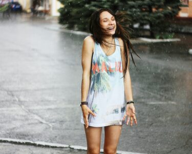woman in white tank top and blue denim shorts standing on road during daytime