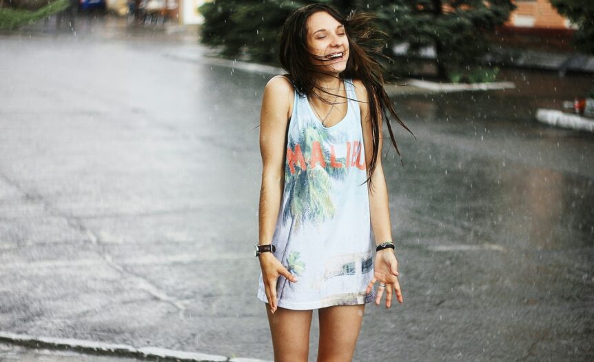 woman in white tank top and blue denim shorts standing on road during daytime