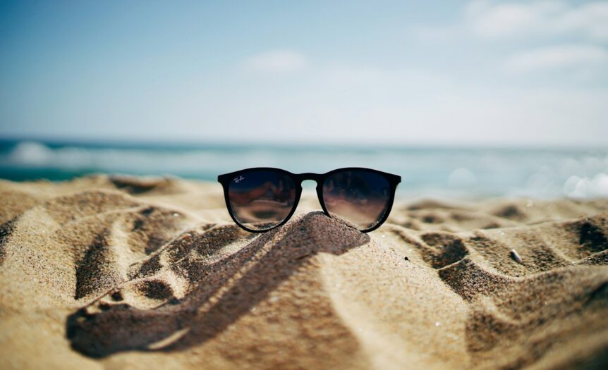 black Ray-Ban Wayfarer sunglasses on beach sand