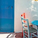 two chairs and a table in front of a blue door