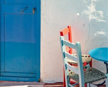 two chairs and a table in front of a blue door
