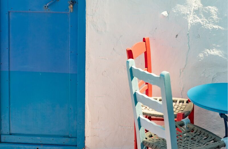 two chairs and a table in front of a blue door