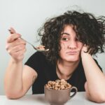 Διατροφή woman with messy hair wearing black crew-neck t-shirt holding spoon with cereals on top