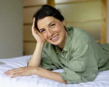 a woman laying on top of a bed next to a laptop computer