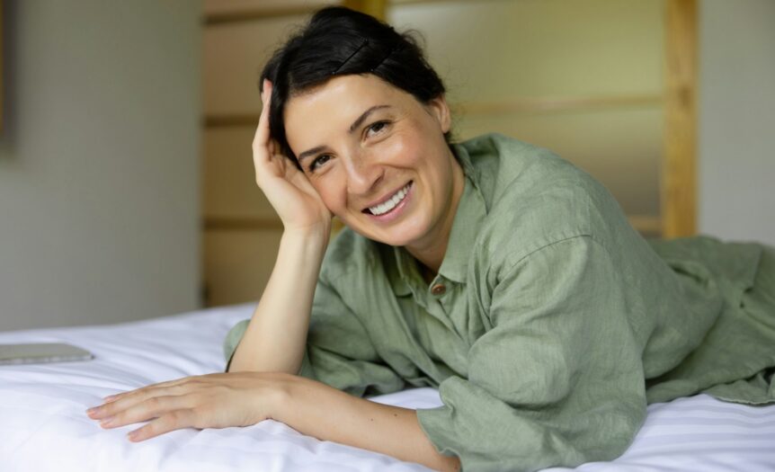 a woman laying on top of a bed next to a laptop computer
