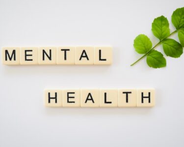 the word mental health spelled with scrabbles next to a green leaf