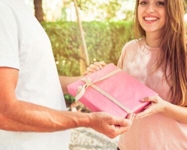 smiling woman giving valentine gift her boyfriend