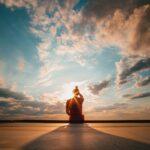 person sitting and facing back under blue and white sky