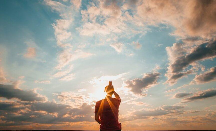person sitting and facing back under blue and white sky