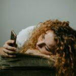 woman in gray sweater holding smartphone