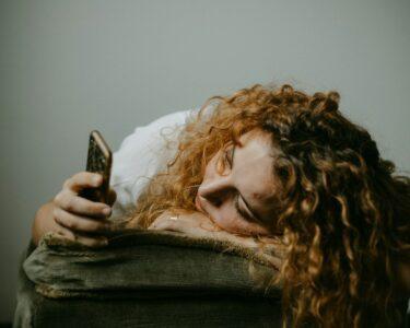 woman in gray sweater holding smartphone
