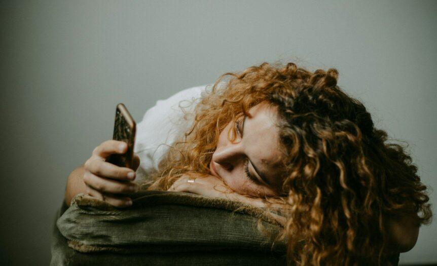 woman in gray sweater holding smartphone