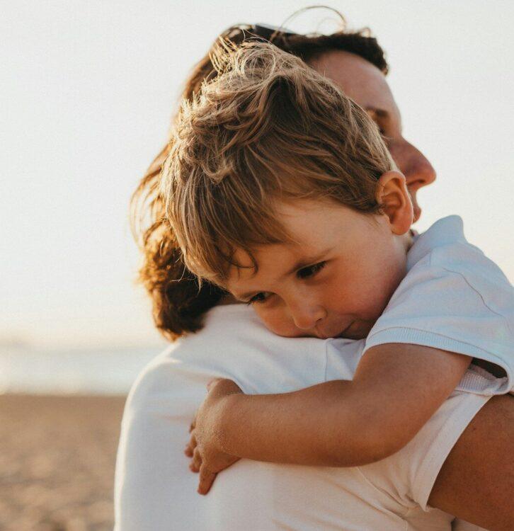 boy hugging woman during daytime
