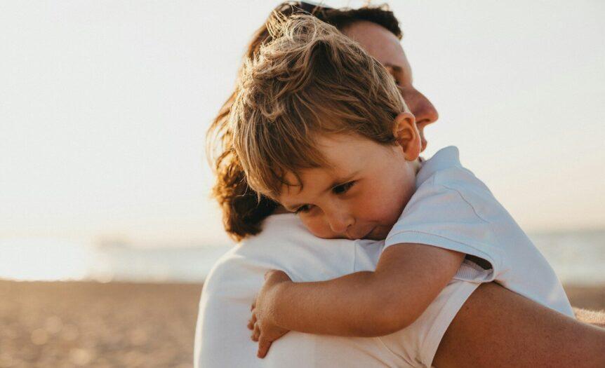boy hugging woman during daytime