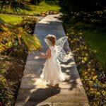 girl wearing angel costume standing on wooden pathway