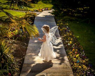 girl wearing angel costume standing on wooden pathway
