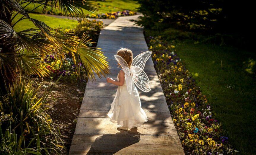 girl wearing angel costume standing on wooden pathway