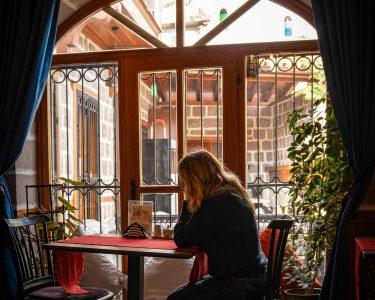 Γυναίκα κάθεται μόνη δίπλα σε παράθυρο σε ήσυχο χώρο — μοναξιά της Κυριακής