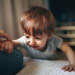 boy in gray and white striped shirt sitting on floor