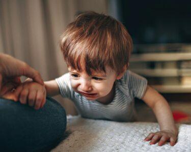 boy in gray and white striped shirt sitting on floor